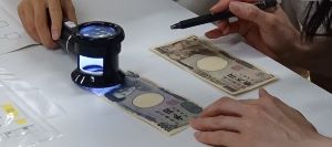 ルーペでマイクロ文字を確認している様子