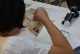 お札に見立てた券を使って鑑定体験をする児童