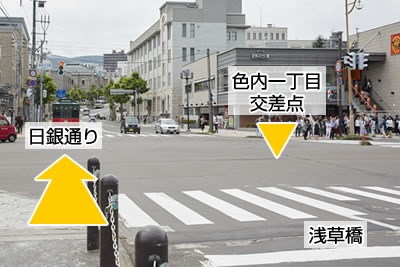 小樽運河の浅草橋前にある色内一丁目交差点から日銀通りを撮影した写真で、日銀通りの左側歩道を歩くように指示しています