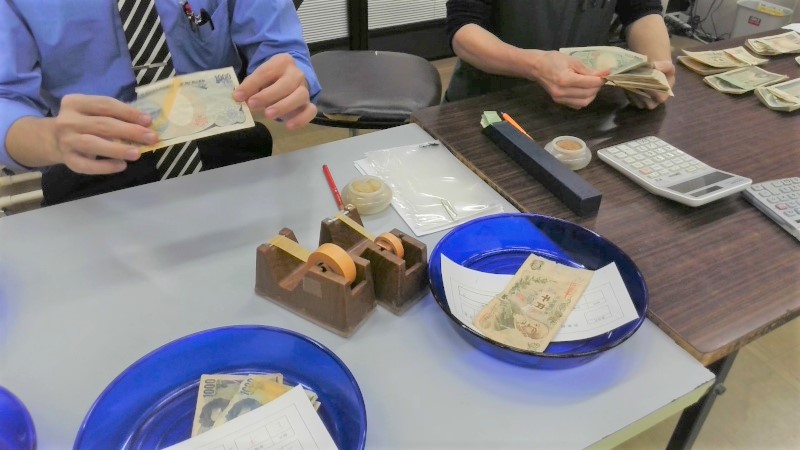 敗れたお札が本物かどうかを調べている様子