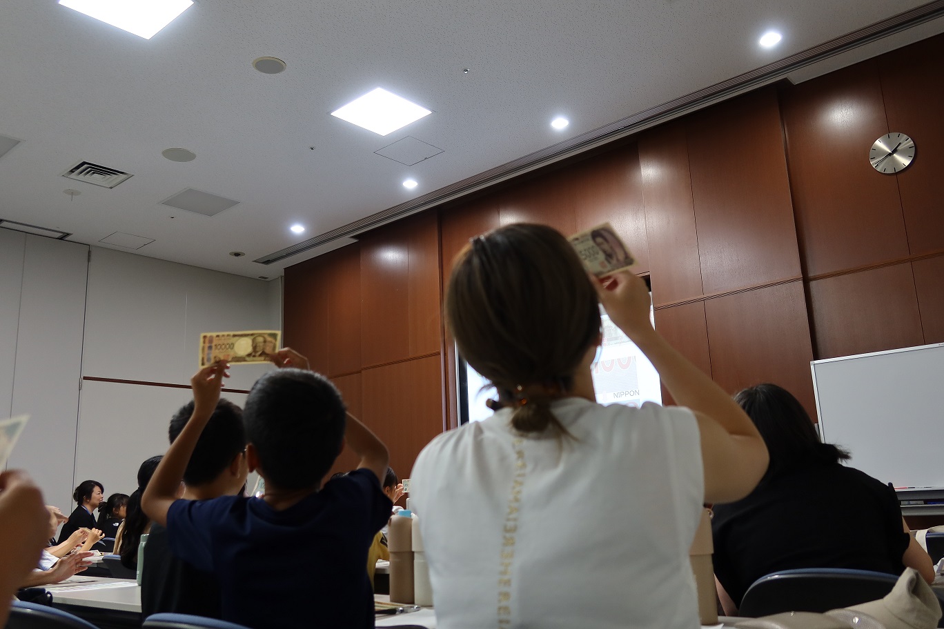 親子教室の様子、お札の偽造防止技術を確認している親子の様子
