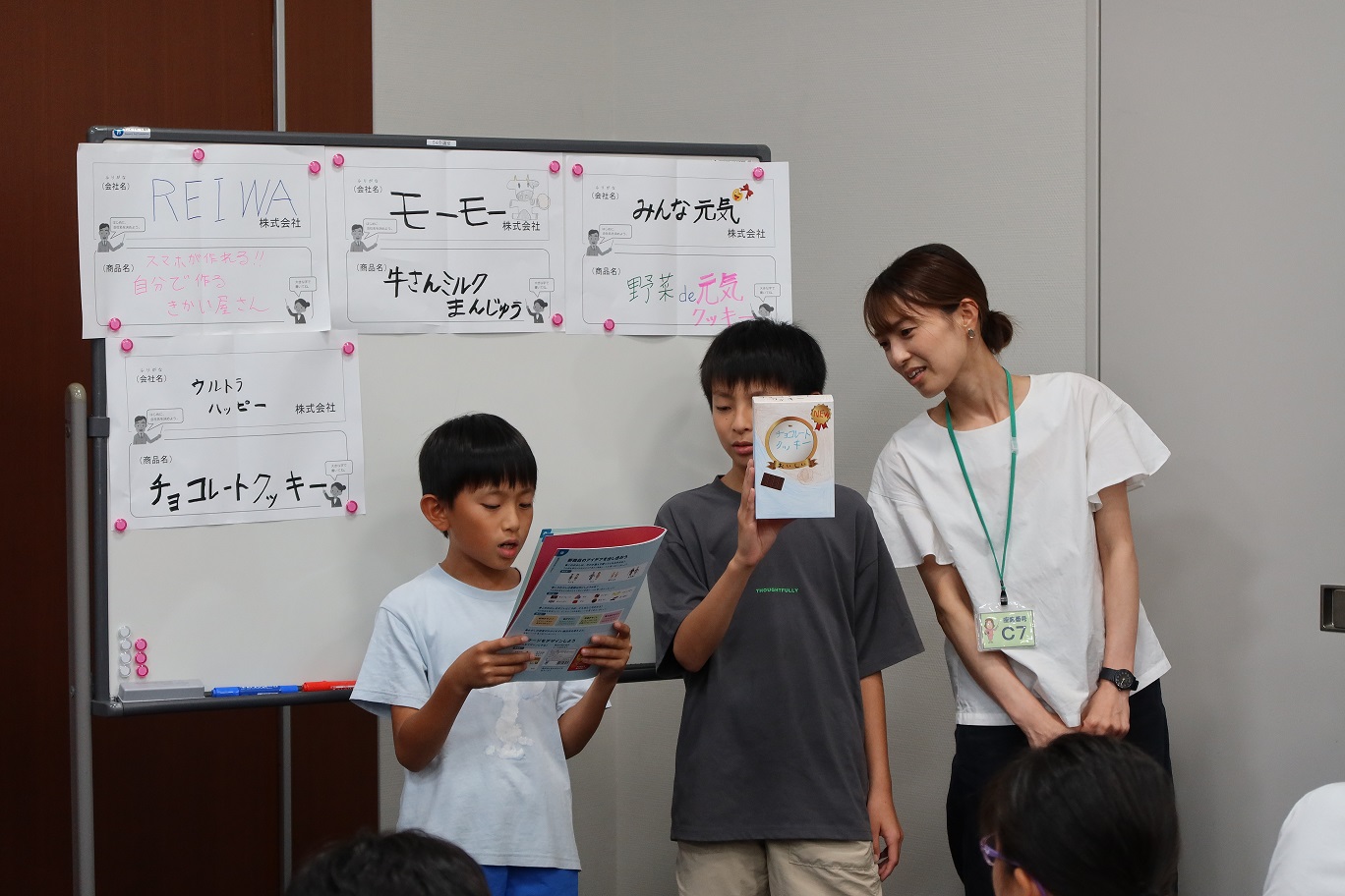 親子教室の様子、親子で考えたお菓子会社の特徴などを、他の参加者に発表している様子