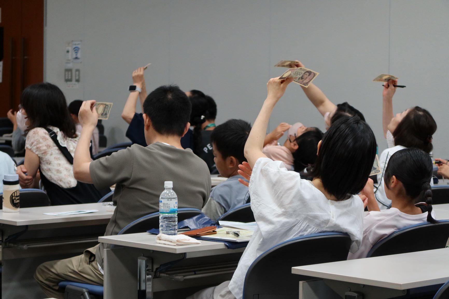 親子教室の様子、お札の偽造防止技術を確認している親子の様子