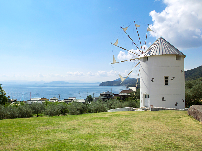 小豆島オリーブ公園内に設置された風車と眼下に望む瀬戸内海の風景の写真です。